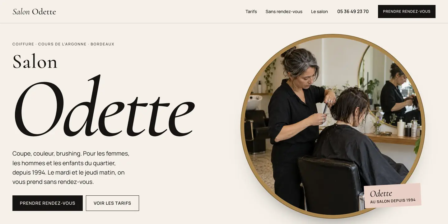 Nouveau site du Salon Odette : nom en grand, photo d'Odette en train de couper dans un miroir rond à cadre laiton, bouton Prendre rendez-vous